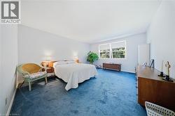 Spacious room with sloped ceiling, blue carpeted flooring, and a large window with white trim - 