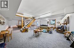 Spacious finished lower level with carpeted flooring, wood-framed window, and exposed wood beam accents - 