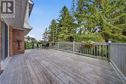 Expansive outdoor deck with gray wood-finish flooring, a coordinating gray railing system, and a brick exterior wall - 