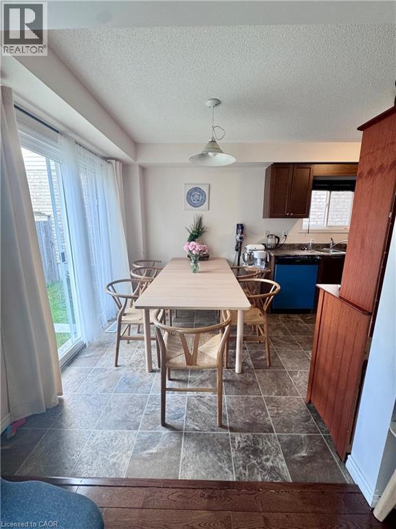 Kitchen and dining area featuring tile flooring, dark wood cabinetry, black countertops, and a sliding glass door to the exterior - 452 Beaumont Crescent, Kitchener, ON