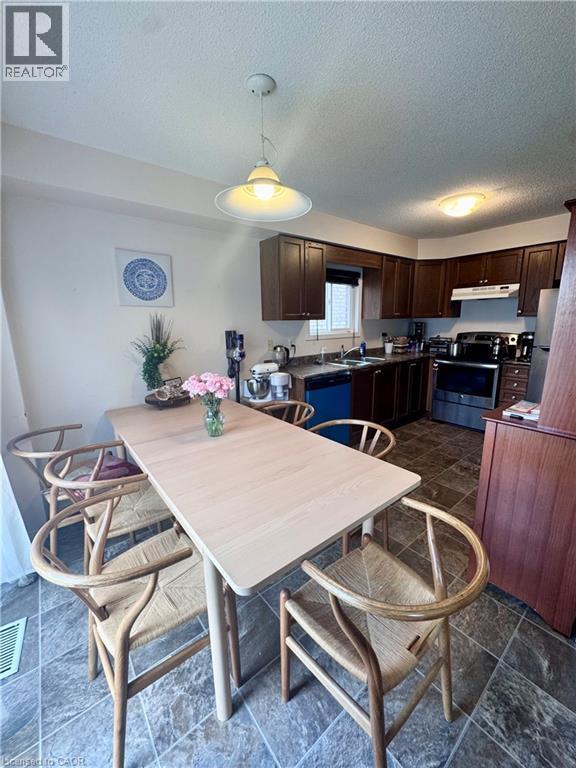 Dining area with tile flooring and a light wood-finish table - 452 Beaumont Crescent, Kitchener, ON