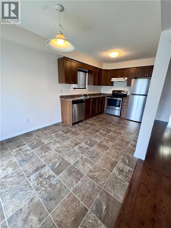 Kitchen featuring dark wood cabinetry, stainless steel appliances, and a tiled floor - 452 Beaumont Crescent, Kitchener, ON