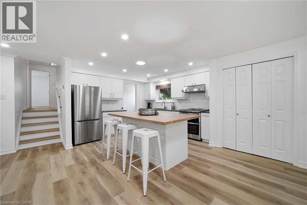 Modern kitchen featuring an island with a wood-finish countertop, stainless steel appliances, white cabinetry, and recessed lighting - 2306 Devon Road, Oakville, ON