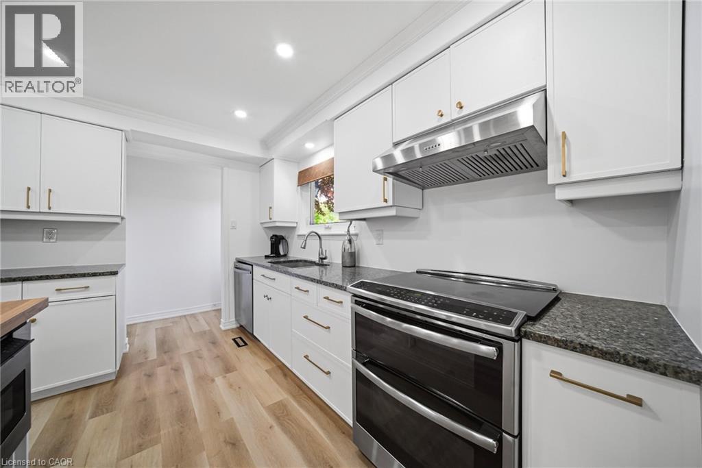 Kitchen featuring white cabinetry with gold-toned hardware, granite countertops, and vinyl flooring - 2306 Devon Road, Oakville, ON