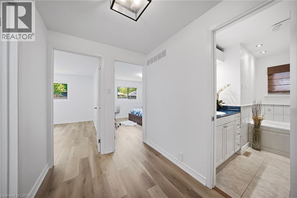 Hallway featuring vinly flooring, white walls, and a modern ceiling light fixture - 2306 Devon Road, Oakville, ON