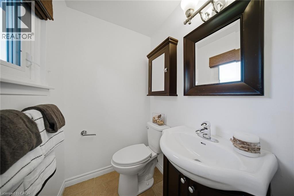 Bathroom featuring a window, built-in medicine cabinet, ceramic toilet, vanity with integrated sink, and polished chrome faucet - 2306 Devon Road, Oakville, ON