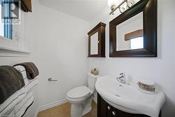 Bathroom featuring a window, built-in medicine cabinet, ceramic toilet, vanity with integrated sink, and polished chrome faucet - 