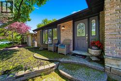 Brick exterior featuring a dark entry door with decorative glass, a bay window, and a concrete entry path with stone retaining walls - 