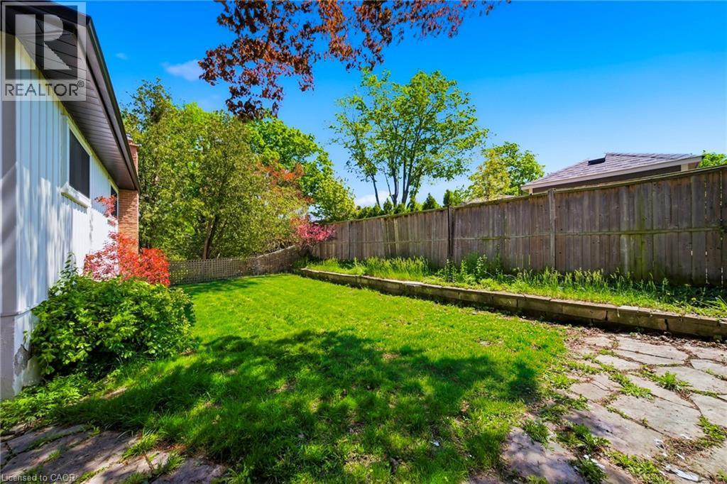 Expansive backyard featuring a green lawn, mature trees, and a full perimeter fence - 2306 Devon Road, Oakville, ON