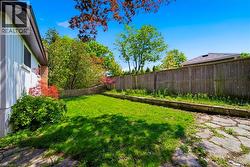 Expansive backyard featuring a green lawn, mature trees, and a full perimeter fence - 