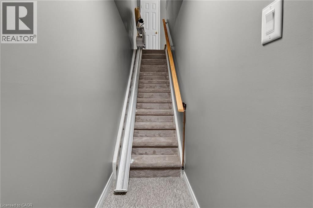 Carpeted staircase with a wooden handrail and a chair lift system to the basement (chair lift is optional) - 159 Thoroughbred Boulevard, Ancaster, ON