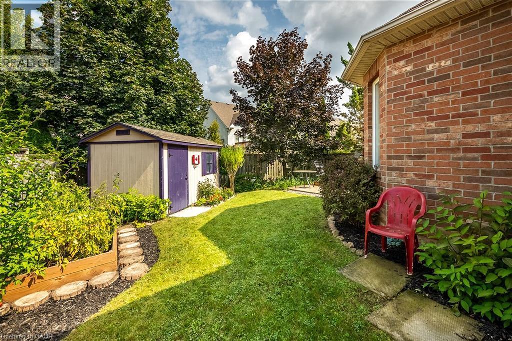 Manicured lawn with mature trees, brick exterior, and a storage shed - 159 Thoroughbred Boulevard, Ancaster, ON
