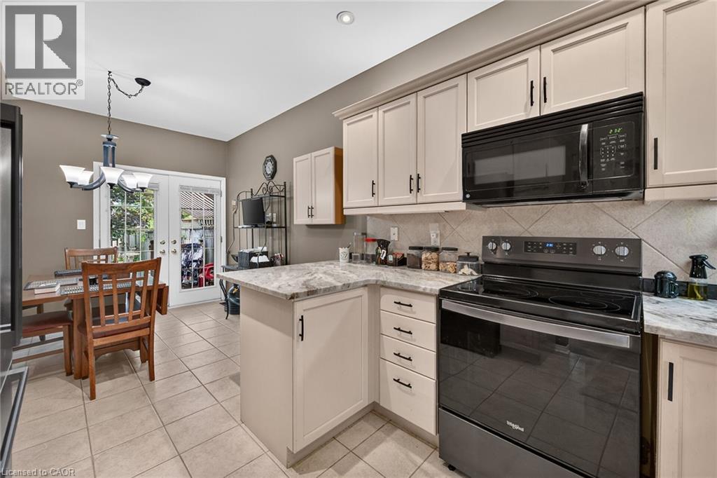Kitchen featuring light cabinetry, solid surface countertops, tile backsplash, and tile flooring - 159 Thoroughbred Boulevard, Ancaster, ON