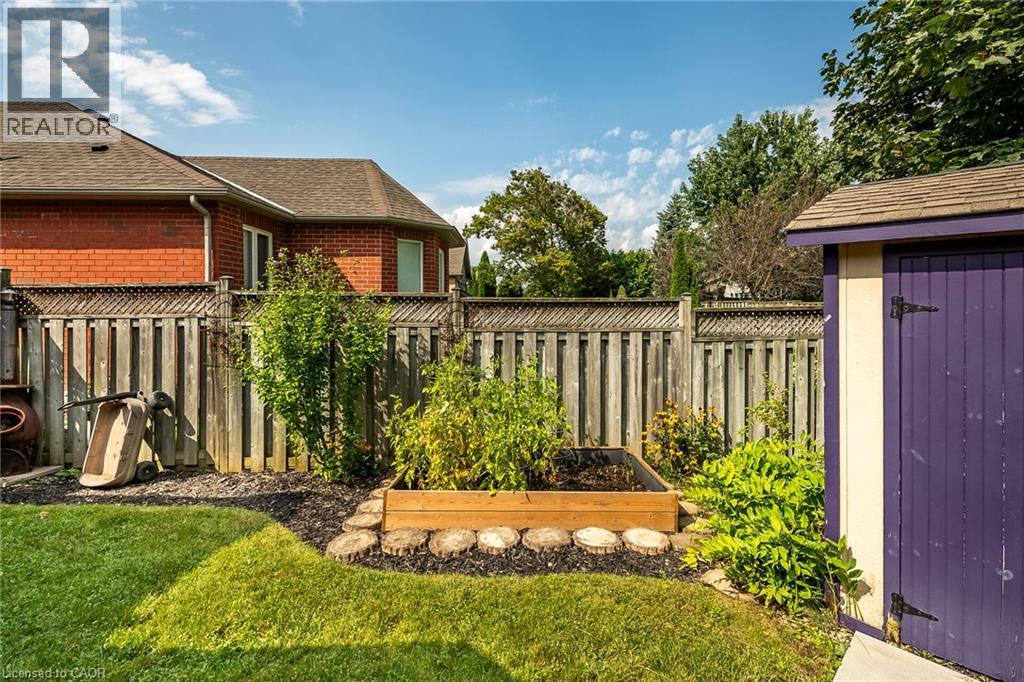 Fenced backyard featuring a raised garden bed, an exterior shed, and mature landscaping - 159 Thoroughbred Boulevard, Ancaster, ON