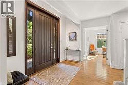 Rich wood-paneled entry door with sidelights, complemented by light wood-finish flooring - 