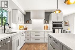 White shaker-style cabinetry, stainless steel appliances, wood-finish flooring, white subway tile backsplash, and quartz countertops - 