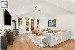 Vaulted ceiling with recessed lighting, wood-finish flooring, wood-burning stove, and multiple glass doors providing outdoor access - 