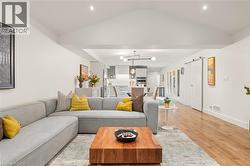 Vaulted ceiling with recessed lighting, wood-finish flooring, and a modern barn door - 