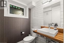 Powder room featuring a wood-finish vanity with a vessel sink, subway tile accent wall, and a horizontal window - 