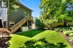 Expansive green lawn with mature trees, established shrubbery, and a wood privacy fence - 