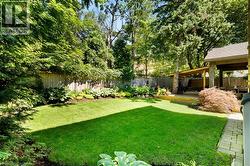 Expansive lawn, mature trees, wood deck, covered patio, and perimeter fencing - 