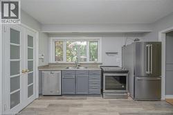 Kitchen featuring stainless steel appliances, gray cabinetry, and wood-finish flooring - 