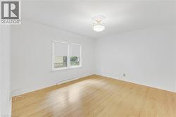 Light wood-finish flooring, white walls, and a semi-flush ceiling light fixture - 