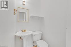 Pedestal sink with gold-tone faucet, framed mirror, and wall-mounted lighting fixture - 