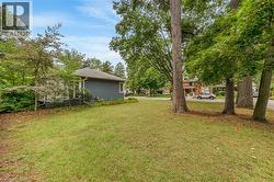 Expansive lawn area with mature trees and a residential street backdrop - 