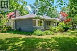 Exterior featuring horizontal siding, multiple prominent windows, a covered front porch with white railings, and a manicured lawn - 