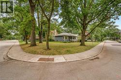 Blue siding exterior, covered porch, multiple mature trees, corner lot, and concrete sidewalks - 