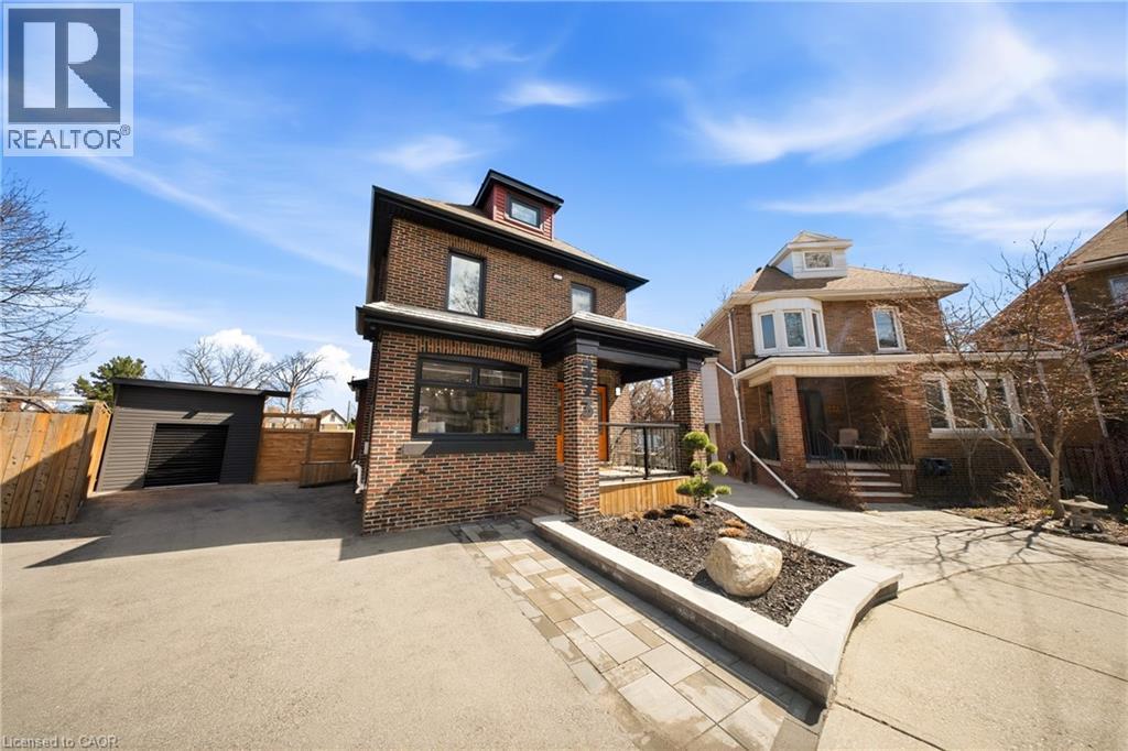 View of front of house featuring an outbuilding, brick siding, asphalt driveway, and a garage - 273 Stinson Crescent, Hamilton, ON