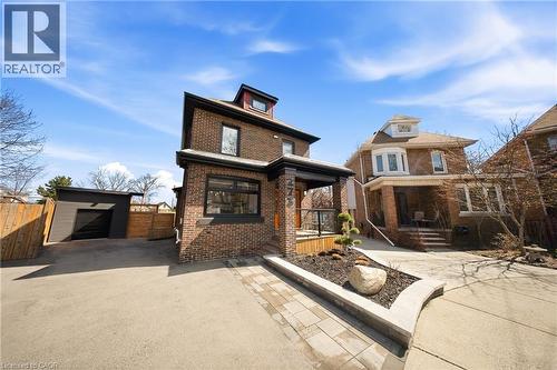 View of front of house featuring an outbuilding, brick siding, asphalt driveway, and a garage - 273 Stinson Crescent, Hamilton, ON 