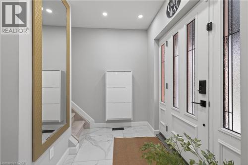Entryway with a white paneled door featuring vertical frosted glass inserts, black hardware, and an adjacent full-length mirror with a gold-tone frame - 273 Stinson Crescent, Hamilton, ON 