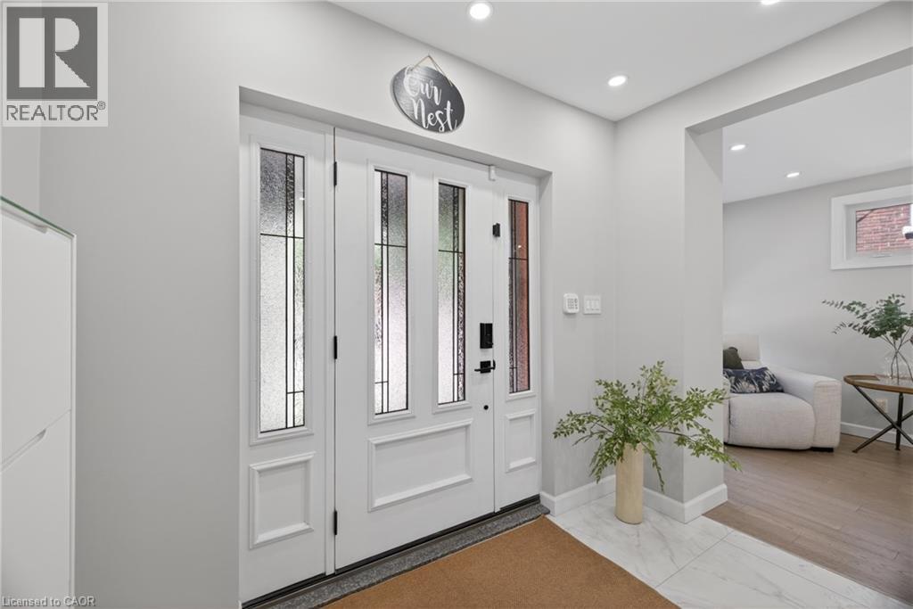 Bright entryway featuring a white paneled door with frosted glass inserts, recessed lighting, and a white tile floor - 273 Stinson Crescent, Hamilton, ON