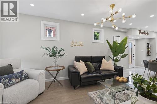 Recessed ceiling lighting and a contemporary brass chandelier illuminate this living space - 273 Stinson Crescent, Hamilton, ON 