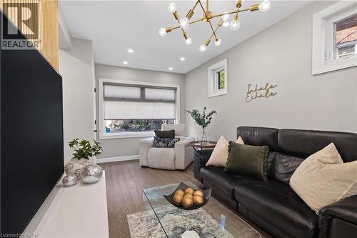 Spacious living area featuring wood-finish flooring, recessed lighting, and a modern gold-tone sputnik chandelier - 273 Stinson Crescent, Hamilton, ON 