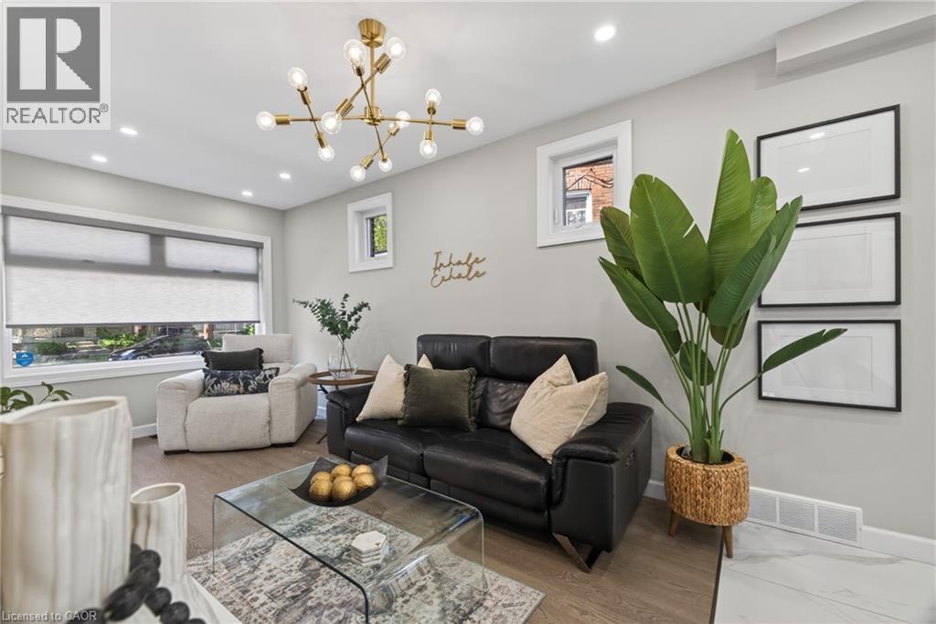 Spacious living area featuring light wood-finish flooring and a contemporary brass multi-bulb chandelier - 273 Stinson Crescent, Hamilton, ON