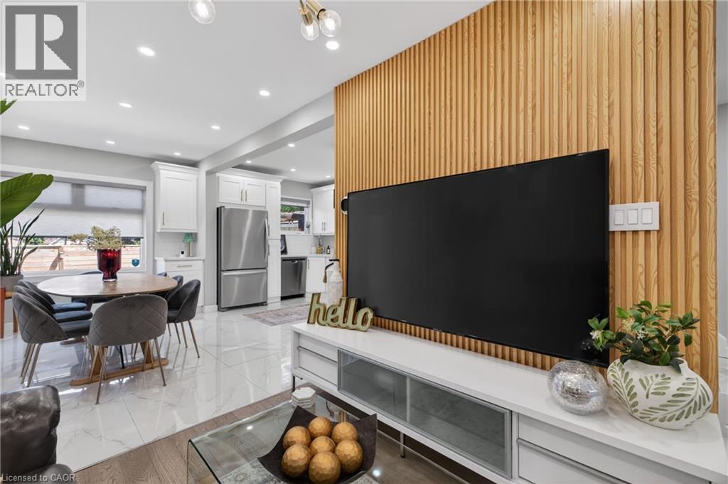 Slatted wood-finish accent wall with integrated media console and overhead lighting - 273 Stinson Crescent, Hamilton, ON