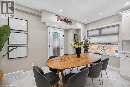 Dining area featuring a wood-finish oval table, recessed ceiling lighting, and white tile flooring - 273 Stinson Crescent, Hamilton, ON 