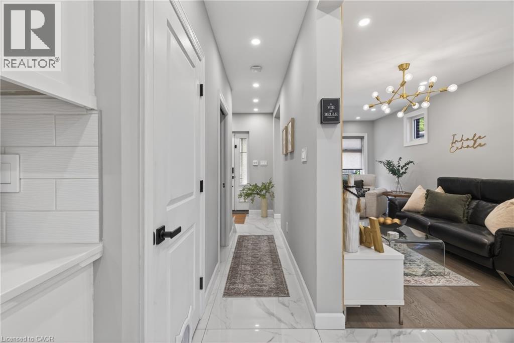 Entryway featuring large-format marble-look tile flooring leading to a living area with wood-finish flooring - 273 Stinson Crescent, Hamilton, ON