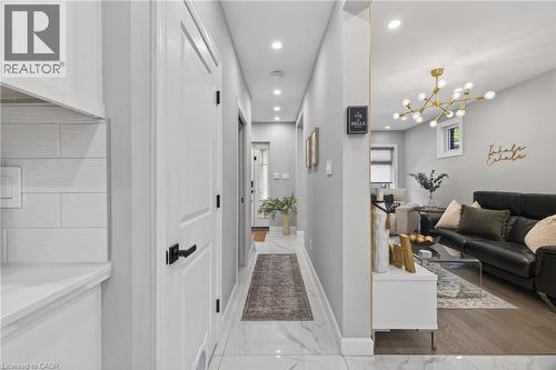 Entryway featuring large-format marble-look tile flooring leading to a living area with wood-finish flooring - 273 Stinson Crescent, Hamilton, ON 