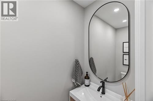 Modern bathroom vanity featuring a rectangular undermount sink, matte black faucet, and oval-framed mirror - 273 Stinson Crescent, Hamilton, ON 