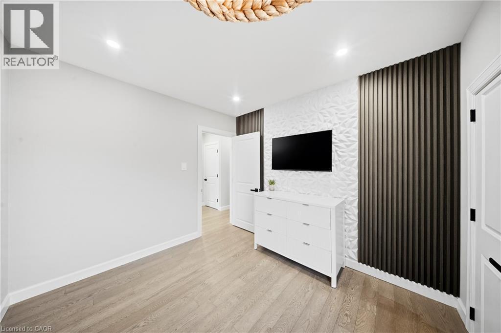 Unfurnished bedroom featuring an accent wall, light wood-type flooring, recessed lighting, and wallpapered walls - 273 Stinson Crescent, Hamilton, ON