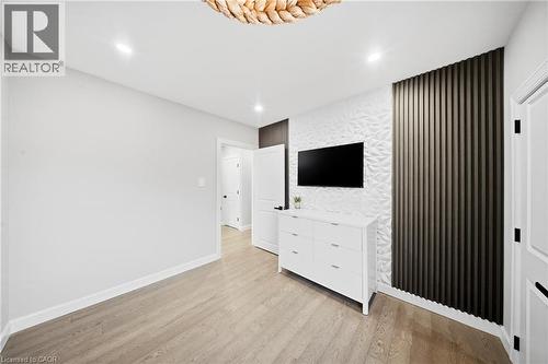 Unfurnished bedroom featuring an accent wall, light wood-type flooring, recessed lighting, and wallpapered walls - 273 Stinson Crescent, Hamilton, ON 