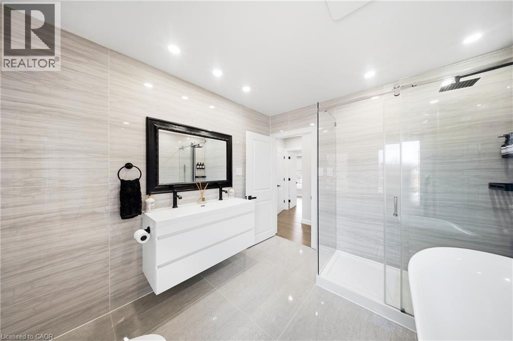 Bathroom featuring tile walls, vanity, a stall shower, light tile patterned floors, and a freestanding bath - 273 Stinson Crescent, Hamilton, ON