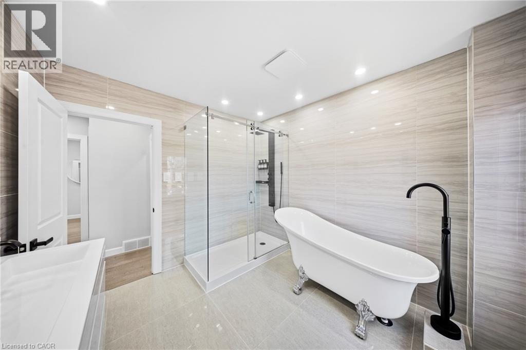 Bathroom with tile walls, a stall shower, vanity, a soaking tub, and light tile patterned floors - 273 Stinson Crescent, Hamilton, ON