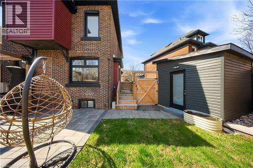 Rear view of property featuring a gate, a patio area, brick siding, an outbuilding, and a yard - 273 Stinson Crescent, Hamilton, ON 