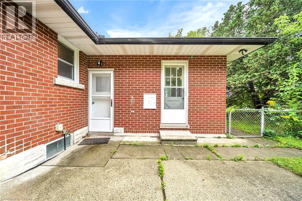 Brick exterior with two entry doors, concrete patio, and fenced-in area - 284 Cedar Crescent, Cambridge, ON
