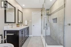 Dual vanity with integrated sinks, frameless glass shower enclosure, recessed shower niche, contemporary lighting, and tiled flooring -